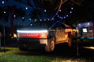 Cybertrucks with American flag wrap and CyberRental.VIP branding illuminated at a nighttime event in South Florida