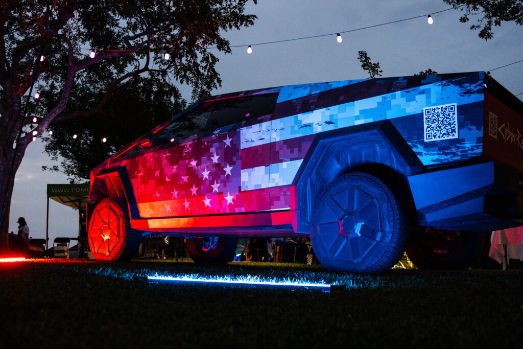 Custom Cybertruck featuring a patriotic vehicle wrap and QR code on display at a South Florida event, highlighting brand visibility through custom cybertruck rentals.